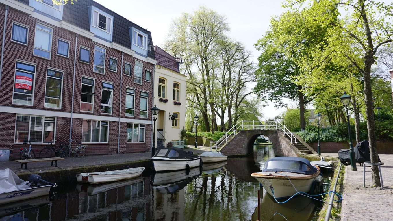 a canal with boats and a bridge in the background