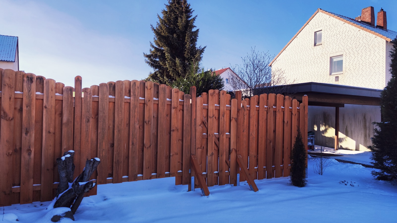 brown wooden fence near green tree under blue sky during daytime