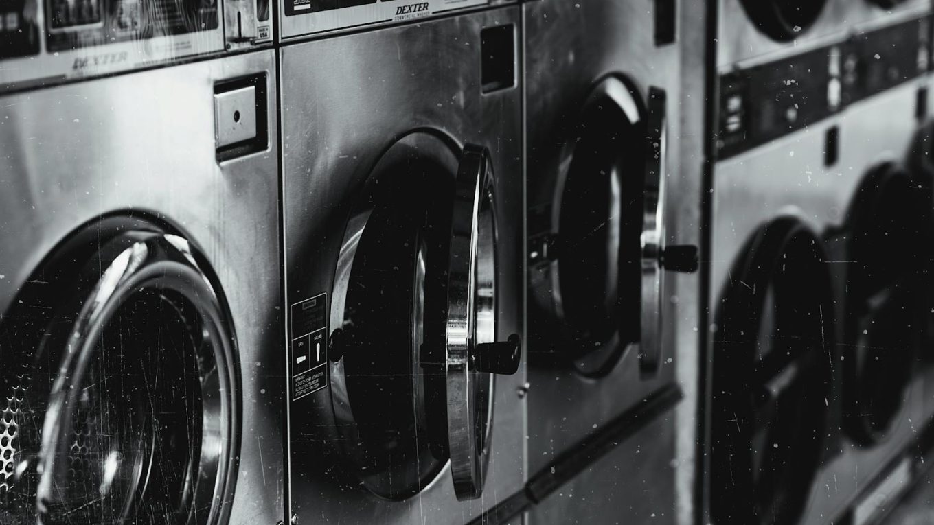 Black and white image of industrial washing machines in a retro style laundry facility.